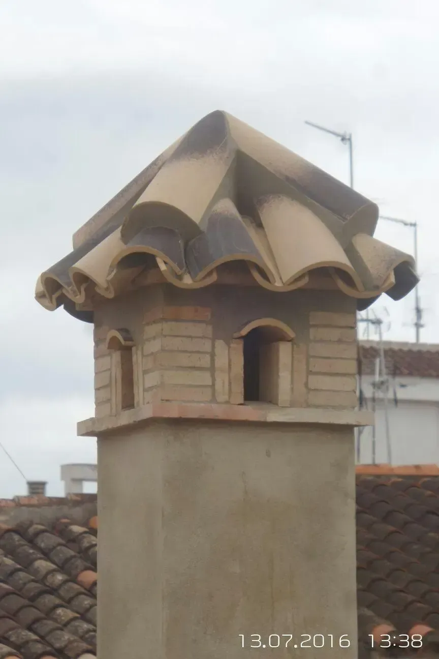 Detalle del remate de tejas de una chimenea de obra