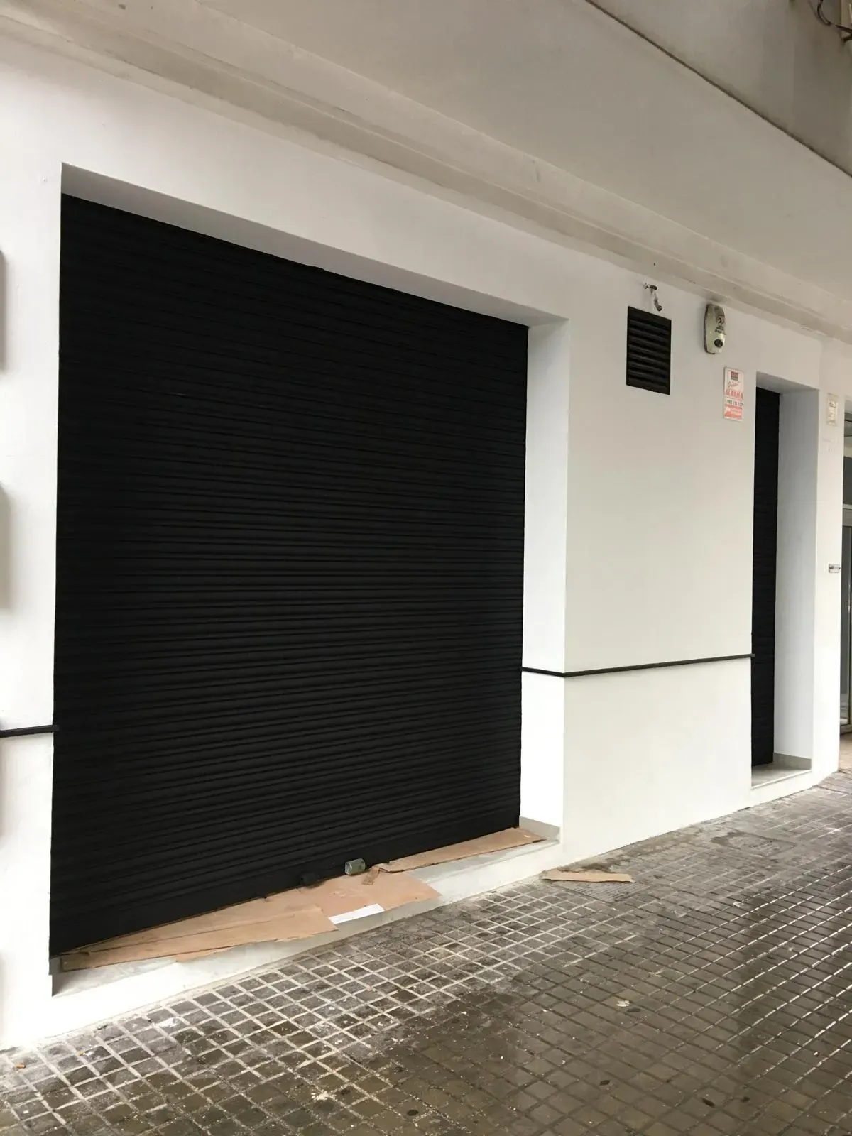 Fachada blanca con persiana negra